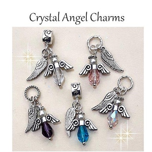 Puede incluir: Crystal Angel Charms. Cinco colgantes de &aacute;ngel plateados con cuentas de cristal en colores transparente, rosa, morado, azul e iridiscente. Cada colgante presenta alas y una cuenta. El texto "Crystal Angel Charms" est&aacute; en la parte superior.