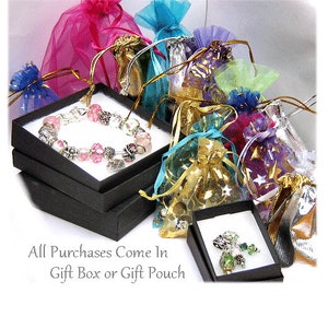 Puede incluir: Un brazalete con cuentas rosas y plateadas exhibido en una caja de regalo negra, rodeado de coloridas bolsas de regalo de organza. El texto "All Purchases Come In Gift Box or Gift Pouch" es visible.