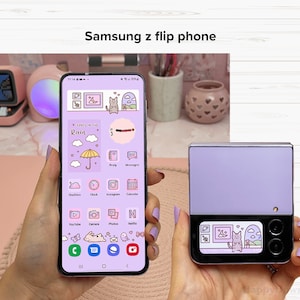 May include: A purple Samsung z flip phone with a cute cartoon cat and clouds on the screen. The phone is closed and the back is a solid purple color.