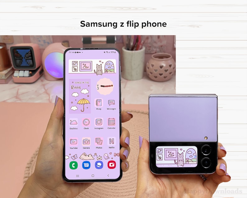 May include: A purple Samsung z flip phone with a cute cartoon cat and clouds on the screen. The phone is closed and the back is a solid purple color.