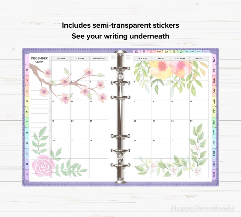 May include: A purple monthly planner with a December 2022 calendar. The planner has a clear plastic cover with a floral design. The floral design includes pink flowers, green leaves, and a pink rose.