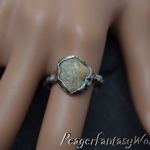 May include: A silver ring with a large, irregular shaped opal gemstone set in a textured silver band.
