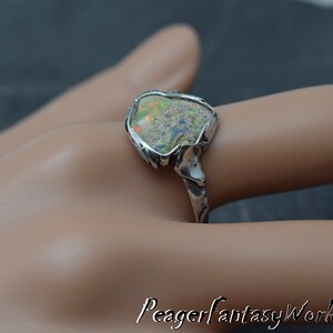 May include: A silver ring with a large, irregular shaped opal gemstone set in a textured silver band.
