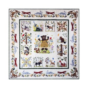 May include: A white quilt with a green border featuring a variety of woodland animals and plants. The center of the quilt features a bear in a beehive with a squirrel, raccoon, moose, deer, and other animals in the surrounding squares.
