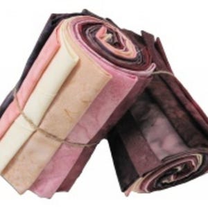May include: A bundle of fabric scraps in shades of pink, peach, and brown, rolled up and tied with twine. The fabric is soft and textured, with a subtle tie-dye effect.