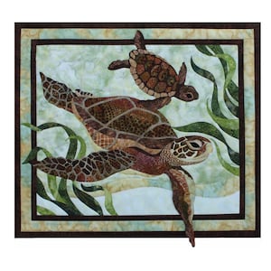 May include: A framed quilted artwork featuring two sea turtles swimming in a green and blue underwater scene. The larger turtle is brown with a detailed shell pattern, while the smaller turtle is a lighter brown with a more simple shell pattern.