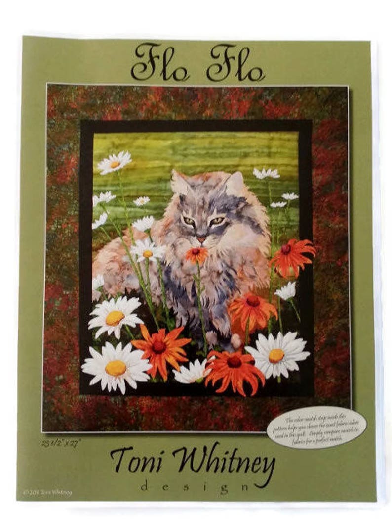 May include: A quilt pattern featuring a gray cat with green eyes sitting in a field of white and orange flowers. The pattern is called "Flo Flo" and is designed by Toni Whitney.