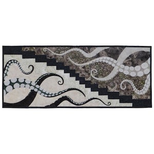 May include: A black and white quilt with a design of octopus tentacles with white polka dots. The tentacles are on a beige background with a black and white geometric pattern.