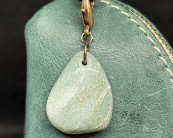 May include: A green leather bag with a brass clasp and a light green stone charm attached.