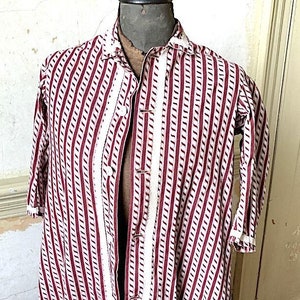 Op de afbeelding: Een lange, gestreepte robe met een witte bies. De robe is gemaakt van een lichtgewicht stof en heeft een knoopsluiting aan de voorkant.