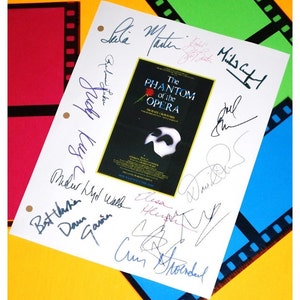 May include: A white sheet of paper with the title "The Phantom of the Opera" and multiple signatures in black, blue, and purple ink. The signatures include names like "Judy Kay", "Elisa", "Dawn", and "Cum Stendal".