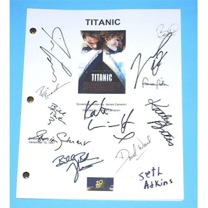 May include: A white script with black ink signatures from the cast and crew of the movie Titanic. The signatures include Kate Winslet, Leonardo DiCaprio, James Cameron, and others. The script has a photo of the Titanic movie poster with the title "Titanic" and the 20th anniversary logo.