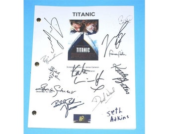 May include: A white script with black ink signatures from the cast and crew of the movie Titanic. The signatures include Kate Winslet, Leonardo DiCaprio, James Cameron, and others. The script has a photo of the Titanic movie poster with the title "Titanic" and the 20th anniversary logo.