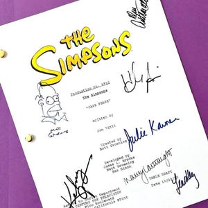 May include: A white paper with the title "THE SIMPSONS" in yellow lettering, featuring signatures and a cartoon sketch. The script is titled "CAPE FEARE" and includes the names of the writers and creators. The paper is held together with gold brads.