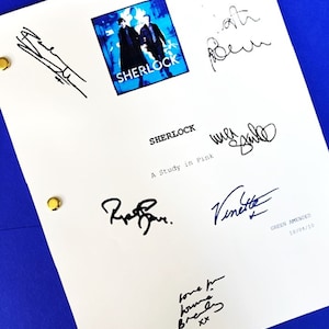 May include: A white script with the title "Sherlock" and the subtitle "A Study in Pink" with several signatures in black ink. The signatures include "Mark Gatiss", "Steven Moffat", "Rupert Graves", "Vinette Robinson", and "Louise Brealey".