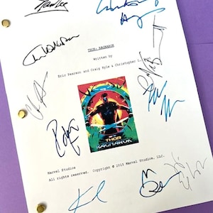 May include: A white script page with a black and white poster of Thor Ragnarok. The script page has several blue and black signatures, including Stan Lee, Chris Hemsworth, and Mark Ruffalo. The text on the script page reads "Thor Ragnarok" and "Written by Eric Pearson and Craig Kyle & Christopher L. Yost". The text on the poster reads "Thor Ragnarok".