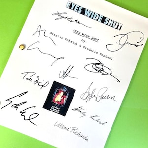 May include: A white script with the title "Eyes Wide Shut" and the names "Stanley Kubrick & Frederic Raphael" written in black ink. The script is signed by several people, including Tom Cruise,  and has a small sticker of the movie poster.