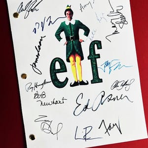 May include: A white script with the word "elf" in large green letters. The script is signed by the cast of the movie "Elf" including Will Ferrell, Zooey Deschanel, Bob Newhart, and Ed Asner.