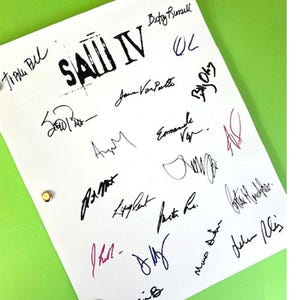 May include: A white page with the title "SAW IV" written in black. The page is signed by various people, including Betsy Russell,  Jann  Van  Patt,  and  various other names.