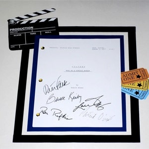 May include: A white framed script for the movie "Cocoon" with signatures from the cast and crew, including Don Ameche, Wilford Brimley, and Hume Cronyn. The script is accompanied by a clapperboard and three movie ticket stubs.
