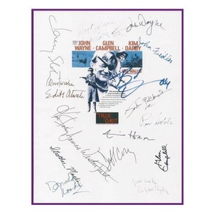 May include: A white sheet of paper with multiple signatures from the cast of the movie "True Grit". The signatures include John Wayne, Glen Campbell, Kim Darby, Strother Martin, Robert Duvall, and others. The movie poster is in the background.