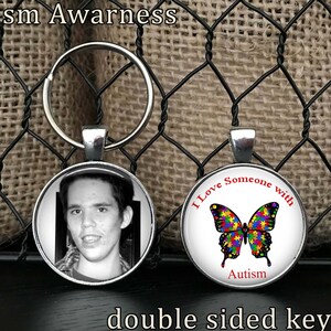 May include: Double-sided keychain with a black and white photo of a person on one side and a colorful butterfly with the text "I Love Someone with Autism" on the other side. Autism Awareness.