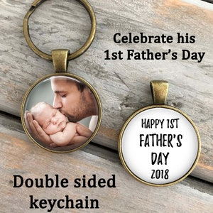 May include: Double-sided keychain with a photo of a father kissing a baby on one side and the text "Happy 1st Father's Day 2018" on the other side.