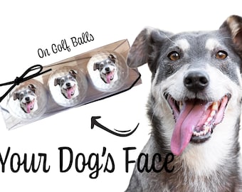 May include: Three white golf balls with a dog's face printed on each. The text "On Golf Balls" is above the golf balls. The text "Your Dog's Face" is below the golf balls. A dog with gray and white fur is smiling with its tongue out.