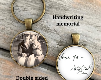 May include: A double-sided round keychain with an antique bronze finish. One side features a black and white photograph of a person and a child. The other side displays black handwritten text on a white background that reads, Love ya - MyBud.