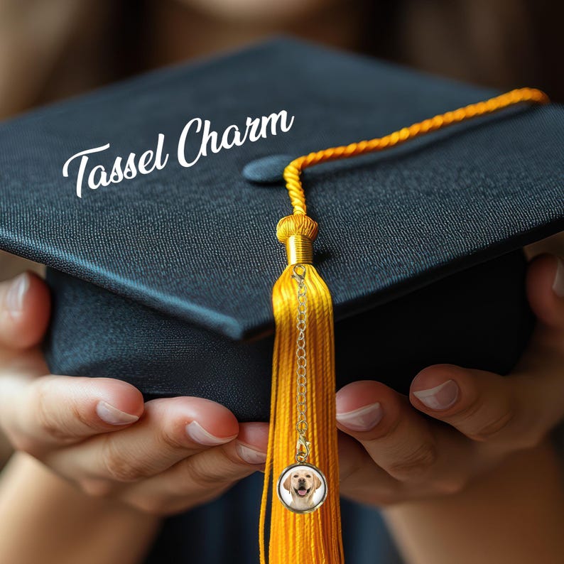 May include: A gold tassel charm with a small picture of a dog on it. The tassel is attached to a graduation cap.
