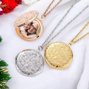 May include: Three gold locket necklaces with floral designs. The lockets are open and one shows a photo of two people.