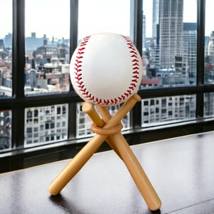 May include: A white baseball with red stitching is displayed on a wooden stand made of two crossed baseball bats.