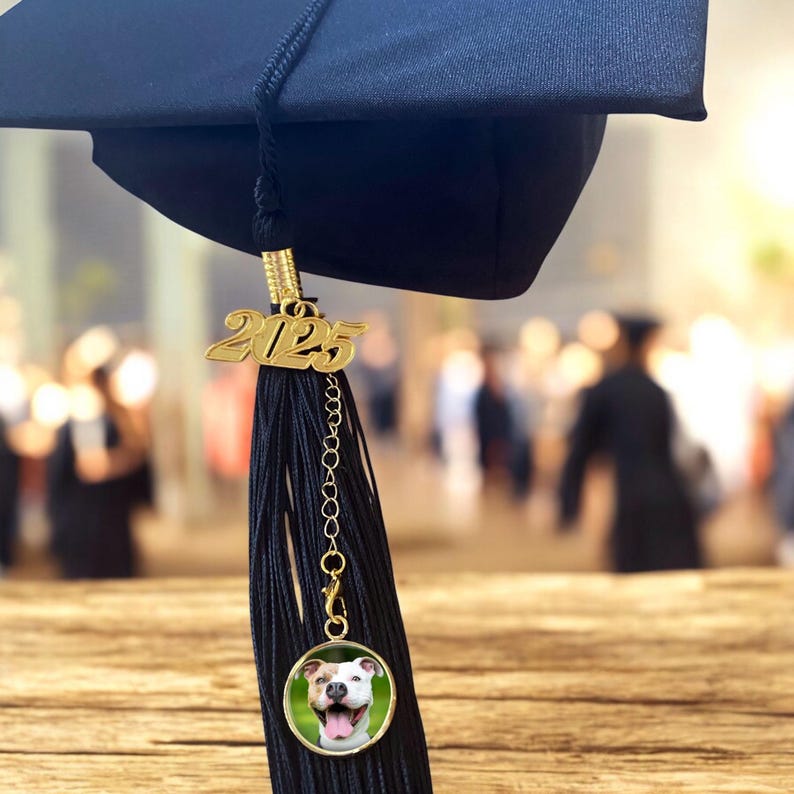 May include: Black graduation tassel with a gold 2025 charm and a round photo charm featuring a dog.