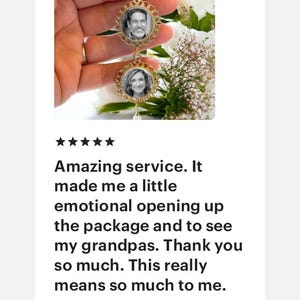 May include: A gold-toned brooch with two round photo frames. The frames are decorated with a filigree design and feature black and white photos of two people. The brooch is attached to a safety pin.