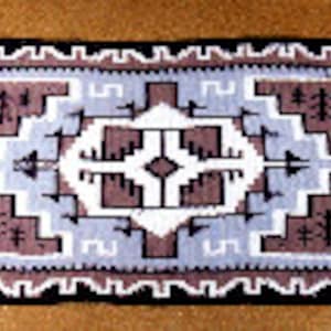 Puede incluir: Una alfombra Navajo negra, blanca y marrón con un patrón geométrico. La alfombra tiene una forma de diamante central con diamantes y triángulos más pequeños que la rodean.