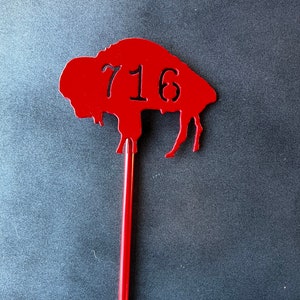 May include: Red metal buffalo silhouette with the number 716 cut out, mounted on a red metal stick.