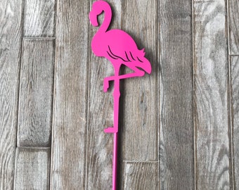 May include: Pink metal flamingo lawn ornament with a long, thin stem. The flamingo is standing on one leg with its head bent back.