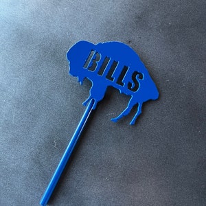 May include: Blue buffalo silhouette with the word "BILLS" cut out, attached to a blue stick.