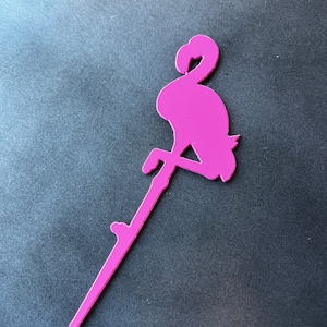 May include: A pink flamingo silhouette with a long, thin stem. The flamingo is standing on one leg with its head bent down. The stem is attached to the flamingo's body.