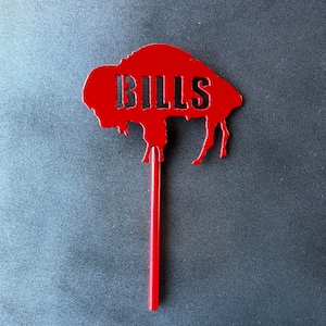 May include: Red metal buffalo silhouette with the word "BILLS" cut out, mounted on a red metal stick.