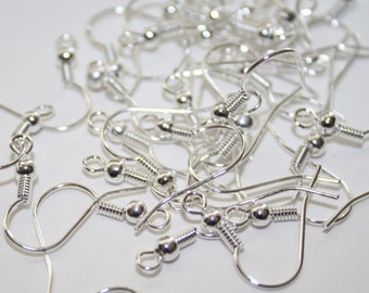 Può includere: Un mucchio di ganci per orecchini color argento con chiusura a molla. I ganci sono in metallo e hanno una piccola sfera all'estremità.