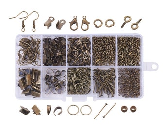 May include: A clear plastic storage box filled with various gold-toned metal jewelry making supplies, including jump rings, clasps, earring hooks, and head pins. The box has eight compartments and is organized by type of jewelry finding.