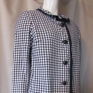 May include: A black and white checkered dress with a black trim and buttons down the front.