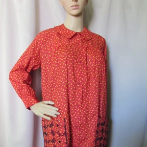 May include: A red and yellow floral print dress with a button-up front and black lace trim on the pockets.