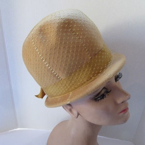 May include: A light brown felt hat with a wide brim and a gold mesh trim. The hat is sitting on a mannequin's head.