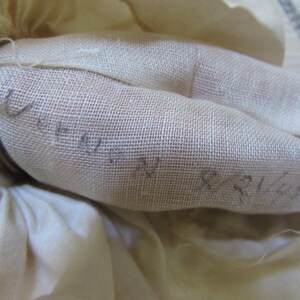 May include: Close-up of a white fabric with a fine mesh texture. The fabric has handwritten text on it, including the words "Unity" and "Peace".