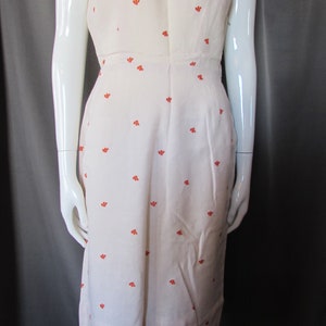 May include: A sleeveless white dress with a small orange floral pattern. The dress has a scoop neckline and a fitted bodice.