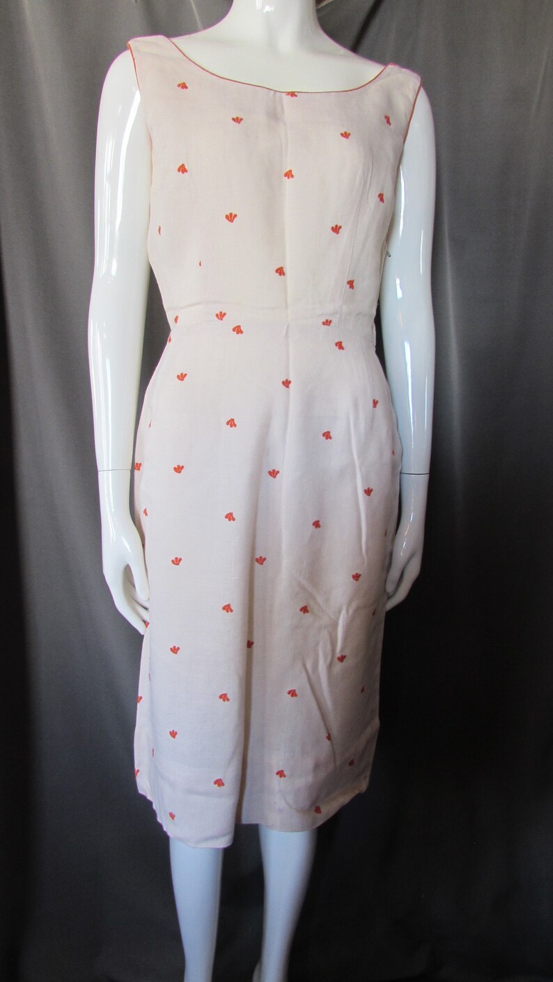 May include: A sleeveless white dress with a small orange floral pattern. The dress has a scoop neckline and a fitted bodice.