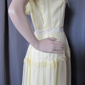 May include: A pale yellow, tiered maxi dress with lace trim and puff sleeves. The dress is made of a sheer fabric and has a fitted bodice.