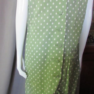 May include: A green dress with white polka dots and a white collar. The dress has a button-up front and a tie at the waist.